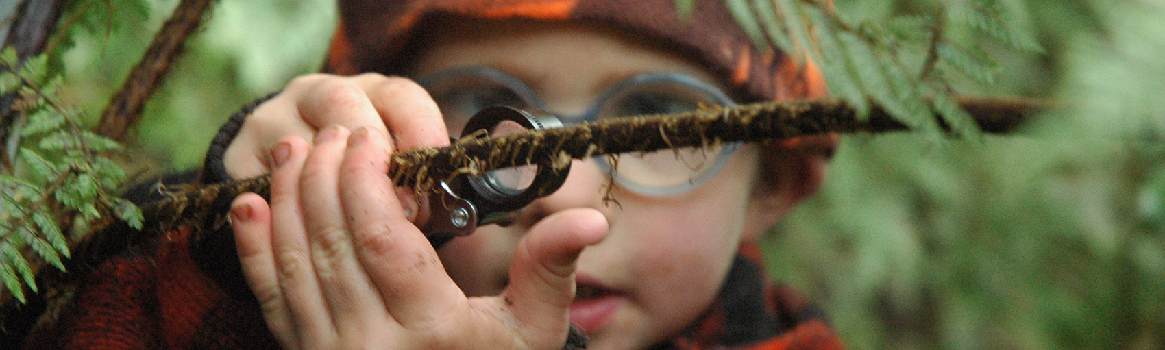 Child using a magnifying glass to look at moss