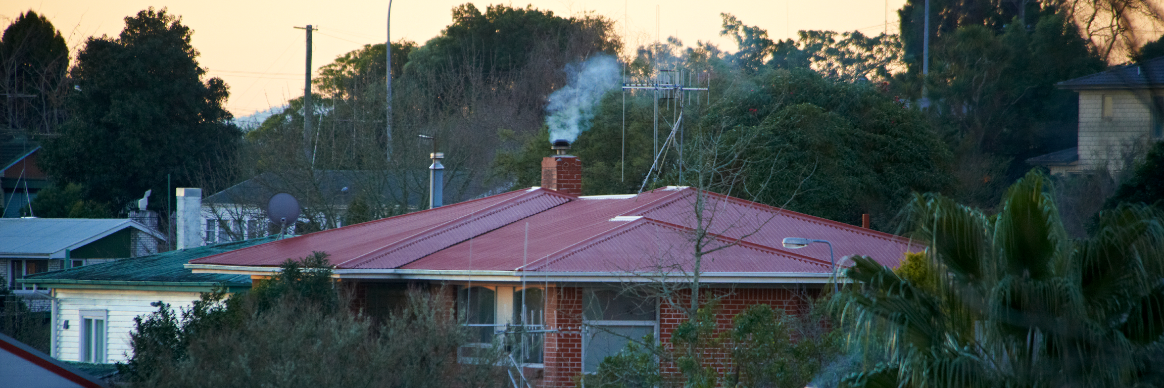 Image of smoke coming out the top of a house chimney